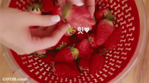 A Person Is Taking A Strawberry Out Of A Bowl Of Strawberries GIF