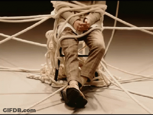 A Person Is Tied Up With Ropes And Sitting On A Chair GIF