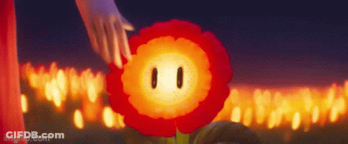 A Person Is Touching A Red Flower With A Face In Front Of A Bunch Of Candles . GIF