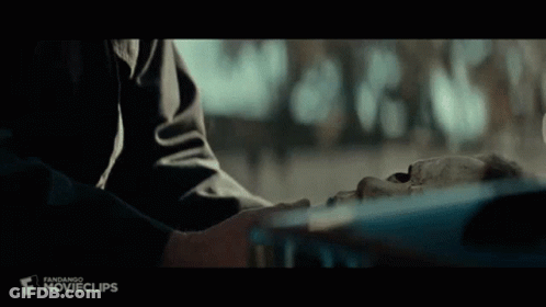 A Person Is Touching A Skeleton 'S Face In A Movie Scene . GIF