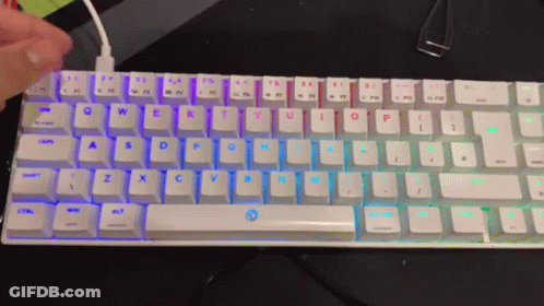 A Person Is Typing On A White Keyboard With A Rainbow Colored Backlight GIF