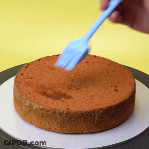 A Person Is Using A Blue Spatula On A Cake GIF