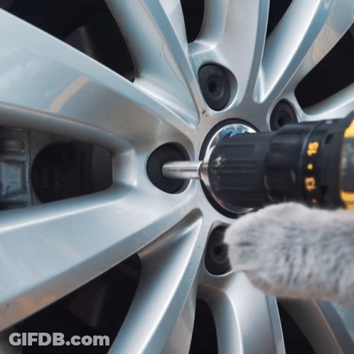 A Person Is Using A Drill To Remove A Screw From A Wheel GIF