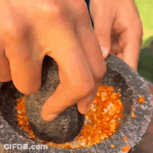 A Person Is Using A Mortar And Pestle To Crush A Vegetable GIF