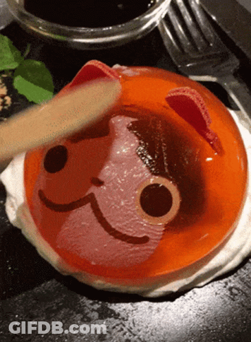 A Person Is Using A Wooden Spoon To Spread Jelly With A Cat Face On It GIF