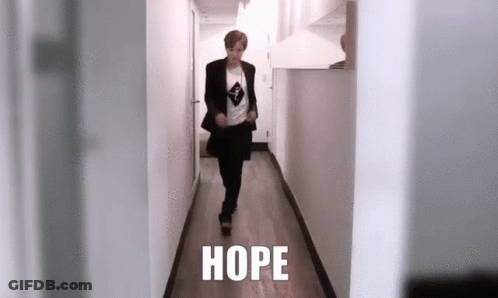 A Person Is Walking Down A Hallway With The Word Hope Written On The Floor . GIF