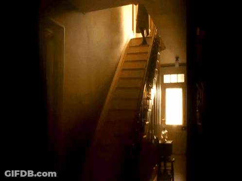 A Person Is Walking Down A Set Of Stairs In A Dark Room GIF