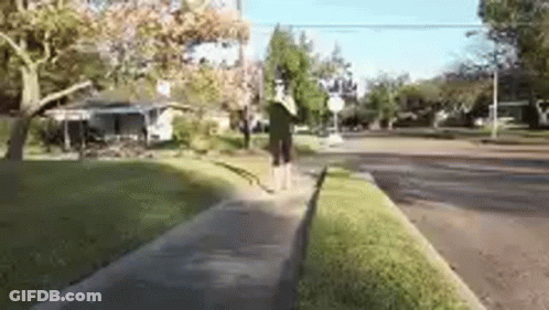 A Person Is Walking Down A Sidewalk In Front Of A House . GIF