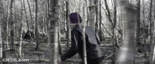 A Person Is Walking Through A Forest With A Rope Around Their Neck . GIF