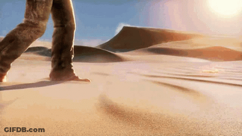 A Person Is Walking Through A Sandy Desert Landscape GIF