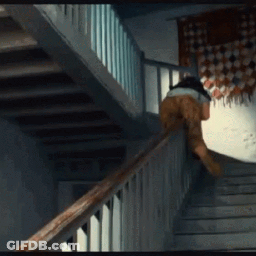 A Person Is Walking Up A Set Of Stairs With A Wooden Railing GIF
