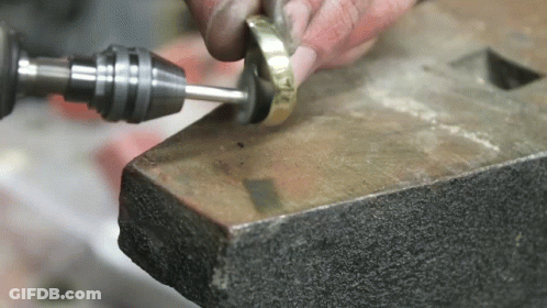 A Person Is Working On A Piece Of Metal With A Drill And Polisher . GIF