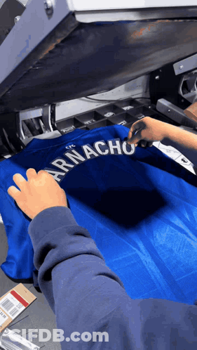 A Person Is Working On A Shirt That Says Armacho On It GIF