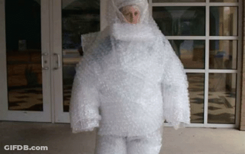 A Person Is Wrapped In Bubble Wrap And Is Standing In Front Of A Building . GIF