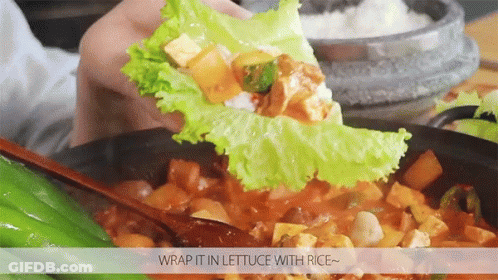 A Person Is Wrapping Lettuce With Rice In A Bowl Of Food GIF