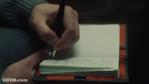 A Person Is Writing In A Notebook With A Pen On Top Of It GIF