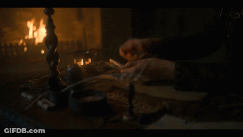 A Person Is Writing In Front Of A Fireplace GIF