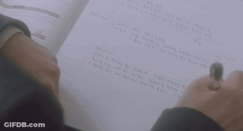 A Person Is Writing On A Piece Of Paper With A Pen GIF
