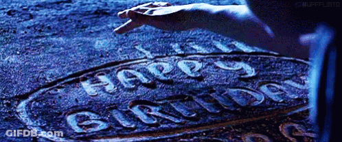 A Person Is Writing The Word Happy Birthday On The Ground . GIF