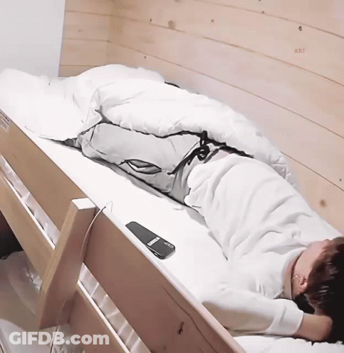 A Person Laying In A Bunk Bed With A Remote Control On The Side GIF
