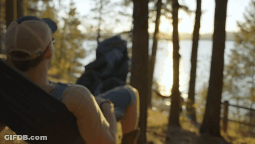A Person Laying In A Hammock With A Backpack Looking At A Lake GIF