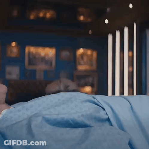 A Person Laying In Bed With A Blue Blanket GIF