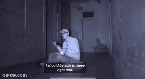 A Person Laying In Sarah 'S Bed With A Flashlight In Their Hand GIF