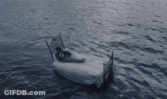 A Person Laying On A Bed In The Middle Of The Ocean GIF