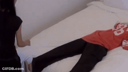 A Person Laying On A Bed Wearing A Red Shirt With The Number 20 On It GIF