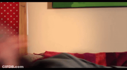 A Person Laying On A Bed With A Red And Purple Striped Blanket GIF