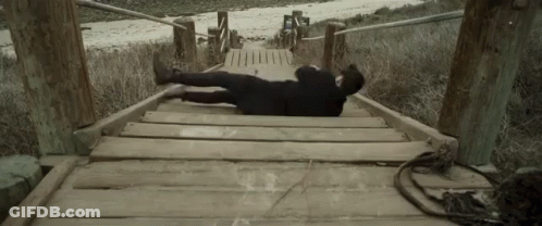 A Person Laying On A Wooden Bridge With Their Feet Up GIF