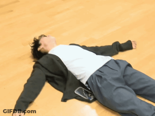 A Person Laying On A Wooden Floor With A Cell Phone In Their Pocket GIF