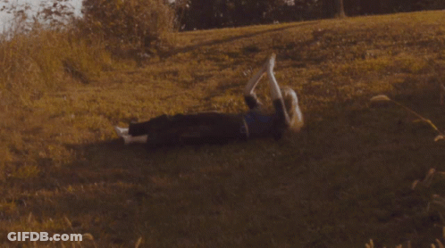 A Person Laying On The Grass With Their Feet In The Air GIF