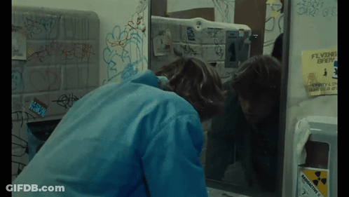 A Person Looking At Their Reflection In A Bathroom Mirror GIF