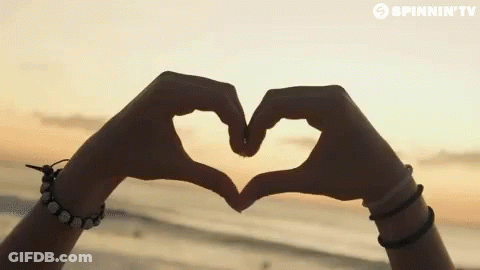 A Person Making A Heart Shape With Their Hands In Front Of A Spinnin ' Tv Banner GIF