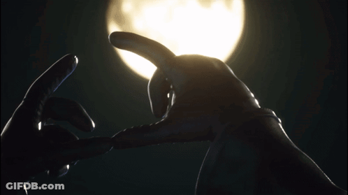 A Person Making A Heart With Their Hands In Front Of A Full Moon GIF