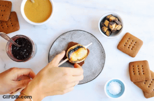 A Person Making A S'mores Sandwich With A Stick GIF