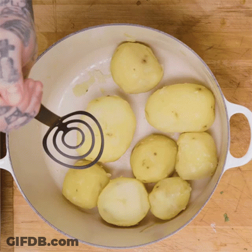 A Person Mashing Potatoes In A White Pot GIF