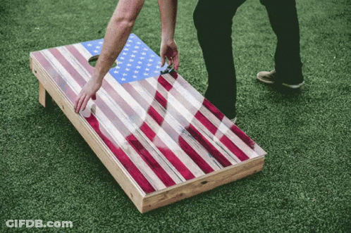 A Person Playing A Game Of Cornhole With An American Flag Design GIF