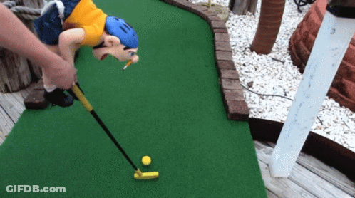 A Person Playing A Game Of Mini Golf With A Monkey Holding A Golf Club GIF