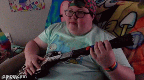A Person Playing A Guitar With A Spongebob Blanket Behind Them GIF