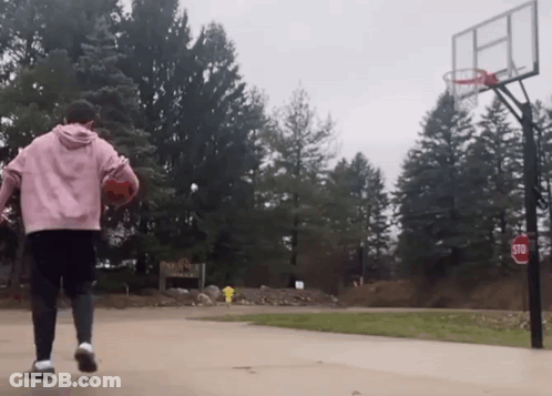 A Person Playing Basketball On A Court With A Stop Sign In The Background GIF