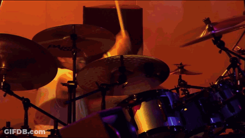 A Person Playing Drums With Paiste Cymbals In The Background GIF