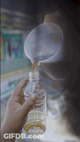 A Person Pouring Liquid Into A Plastic Bottle With A Funnel GIF