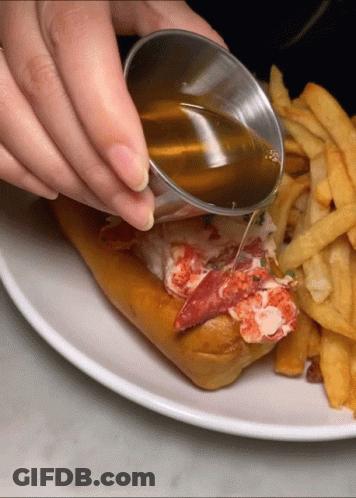 A Person Pouring Maple Syrup On A Lobster Roll GIF