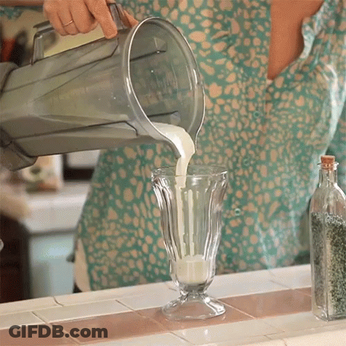 A Person Pouring Milk Into A Glass On A Counter GIF