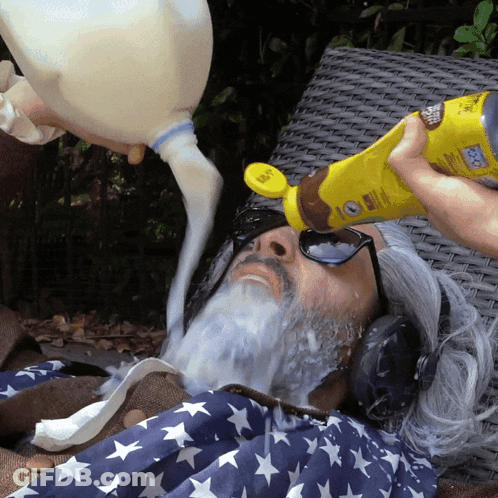 A Person Pouring Milk Into A Man 'S Face With A Bottle That Says Sunscreen On It GIF