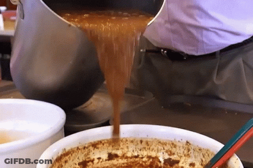 A Person Pouring Something Into A Bowl With A Spoon GIF