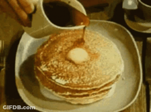 A Person Pouring Syrup On A Stack Of Pancakes GIF