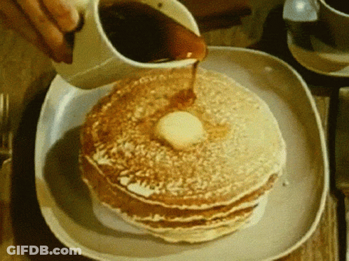 A Person Pouring Syrup On A Stack Of Pancakes GIF
